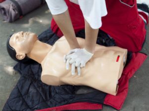 Hands doing chest compressions on a manikin model.