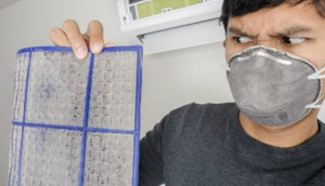 Man wearing air filtering mask, holds dirty air filter.