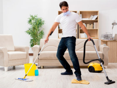 A man cleaning with vacuum and floor mop.