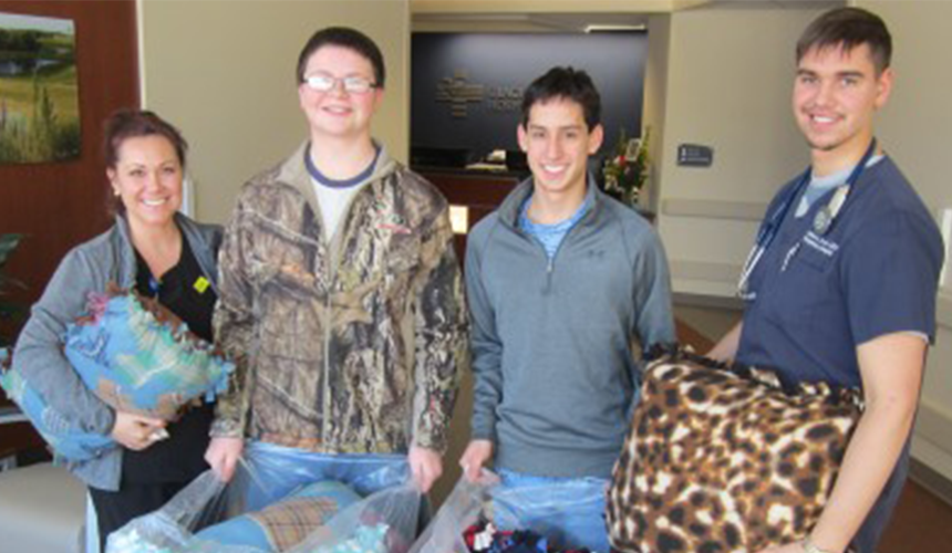 Pillow_Donation_BBE_NHS_020518_FI Two healthcare staff and two teenagers holding pillows in a waiting area.