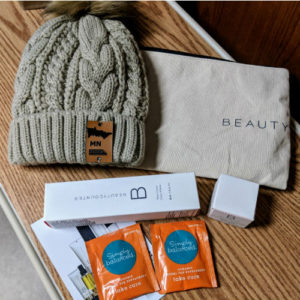 A knit winter hat, small boxes, and a pouch sit on a table.