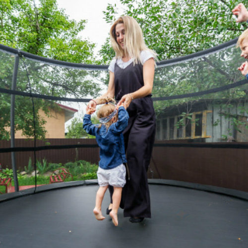 Mom and kids jumping on trampoline.