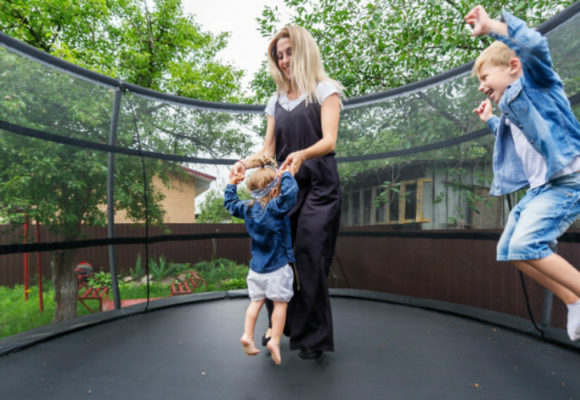 Mom and kids jumping on trampoline.