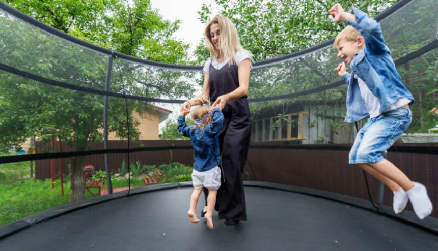 Mom and kids jumping on trampoline.