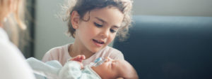 Girl holds newborn baby.