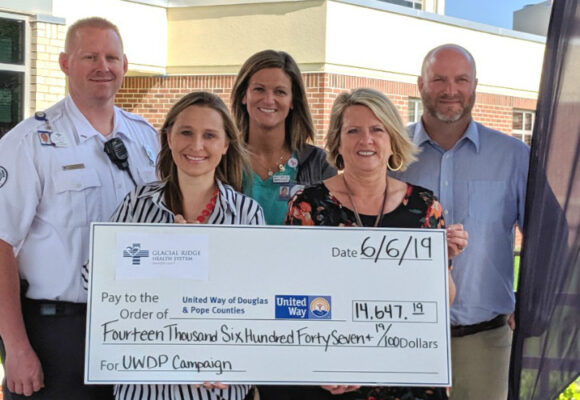 Exterior photo. Five adults holding large check.