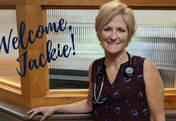 Woman standing next to a glass wall. Text reads Welcome, Jackie!