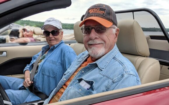 older couple sitting in red convertible