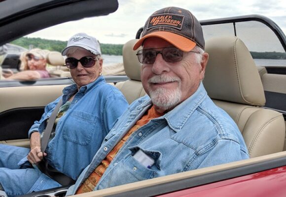 older couple sitting in red convertible