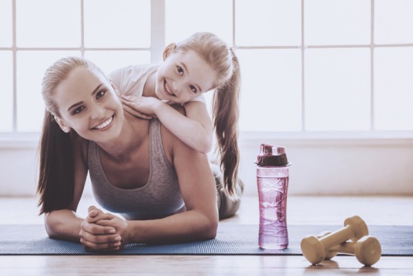 A fit young woman and her daughter take a break from a workout.