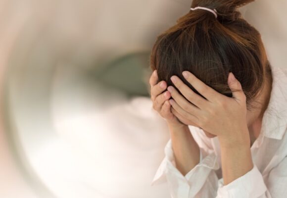 Woman holding head in hands, dizziness concept.