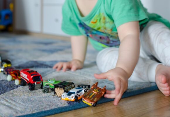 Kid lining up toys on the floor.