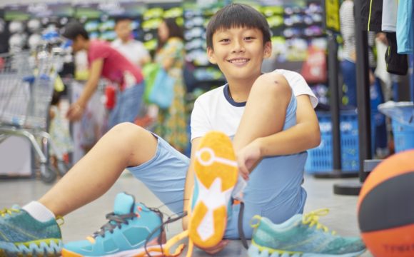 boy smiling trying sports shoes in shopping mall