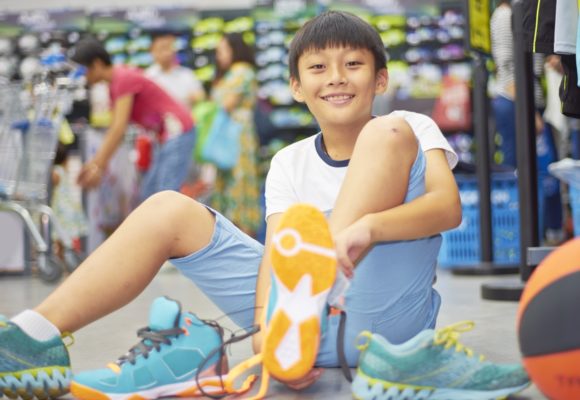 boy smiling trying sports shoes in shopping mall