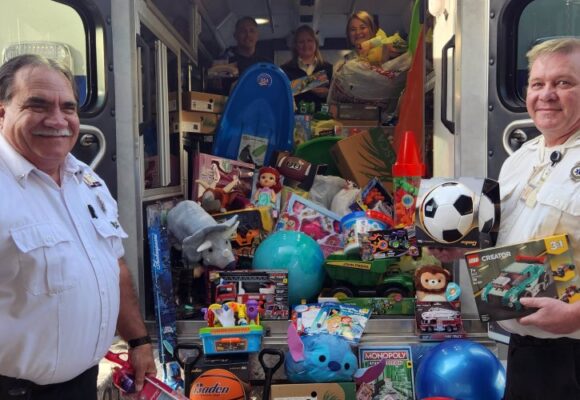 Toys and sleds are piled in the back of an ambulance with staff