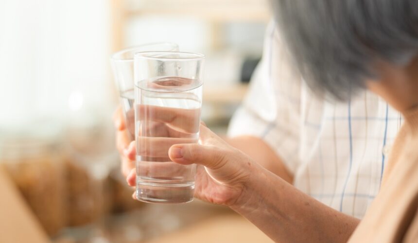 an older couple at home are holding glasses of water