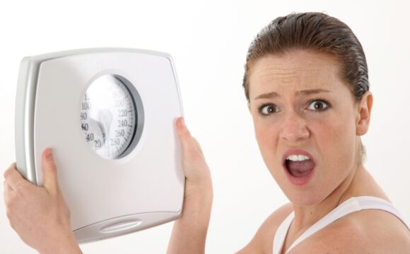 woman with a shocked face holding a white scale