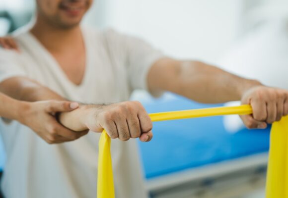 male patient stretching a yellow exercise band at occupational therapy