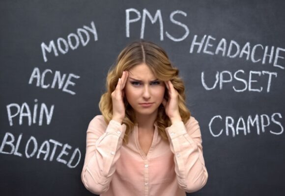 perplexed woman with hands on sides of her head and words on blackboard